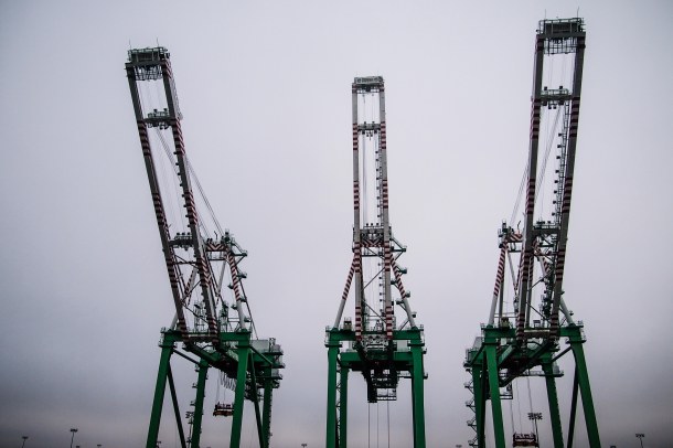 With their arms raised, gantry cranes sit idly at the dock on a foggy day without cargo operations at the port.